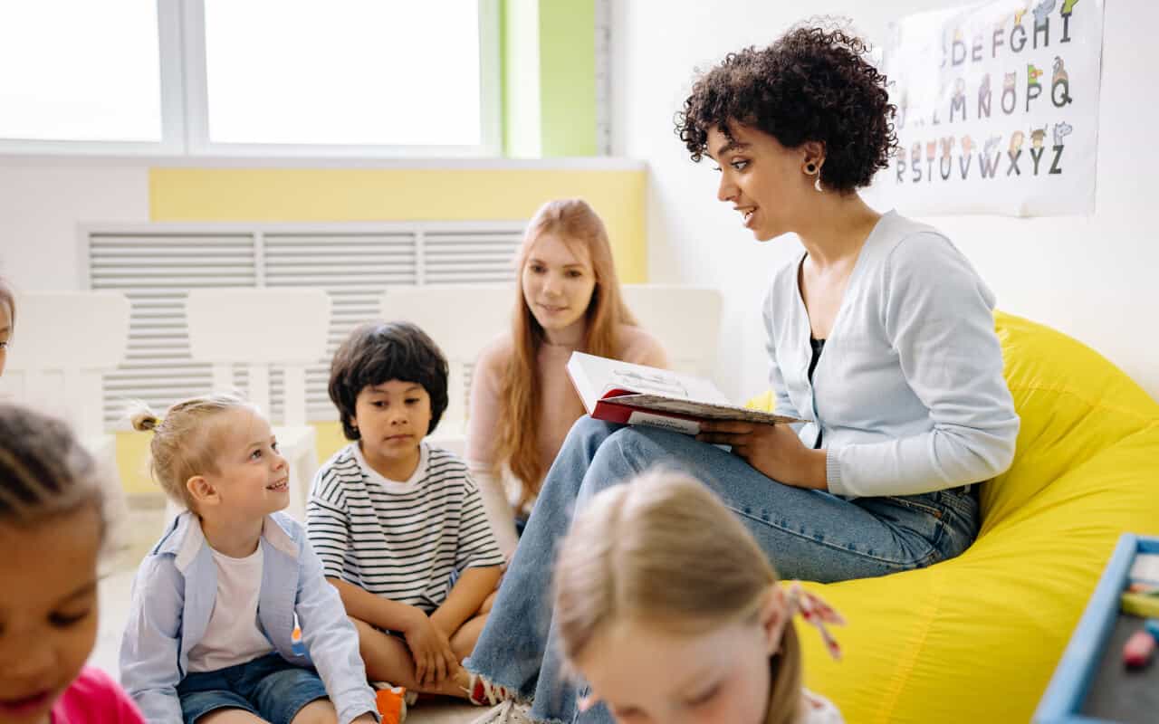Docente leyendo un cuento a niños en aula de kindergarten fomentando la escucha y la comprensión lectora