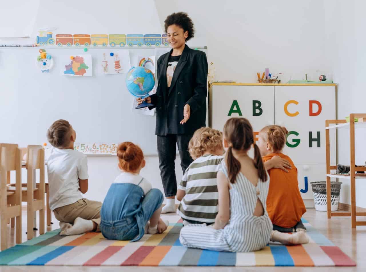 Docente guiando una actividad educativa con niños Toddler en un aula de aprendizaje temprano