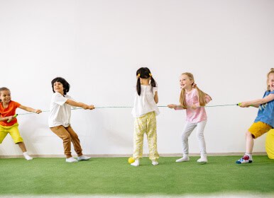 Niños participando en un juego cooperativo que fomenta el trabajo en equipo, la fuerza y la coordinación motriz
