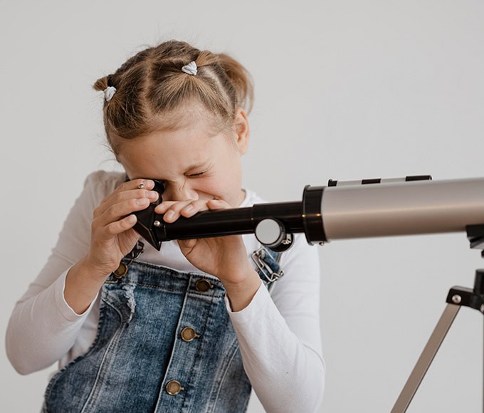 Niña observando con microscopio en kínder Pequeños Encantos.