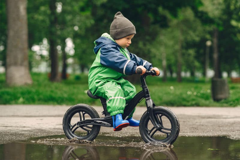 Niño pequeño montando bicicleta de equilibrio al aire libre, desarrollando coordinación y autonomía