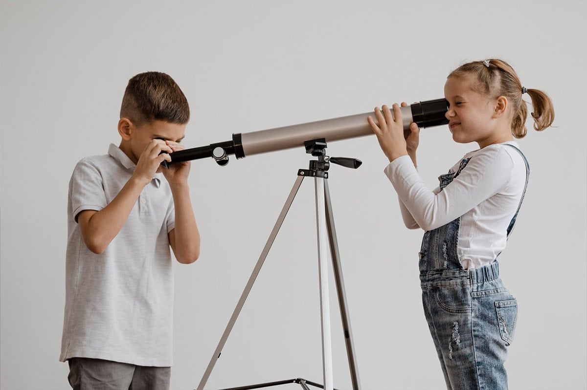 Niños de educación inicial explorando y aprendiendo a través de la observación con telescopio en Pequeños Encantos