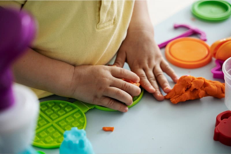 Manos de un niño moldeando plastilina de colores durante una actividad creativa infantil