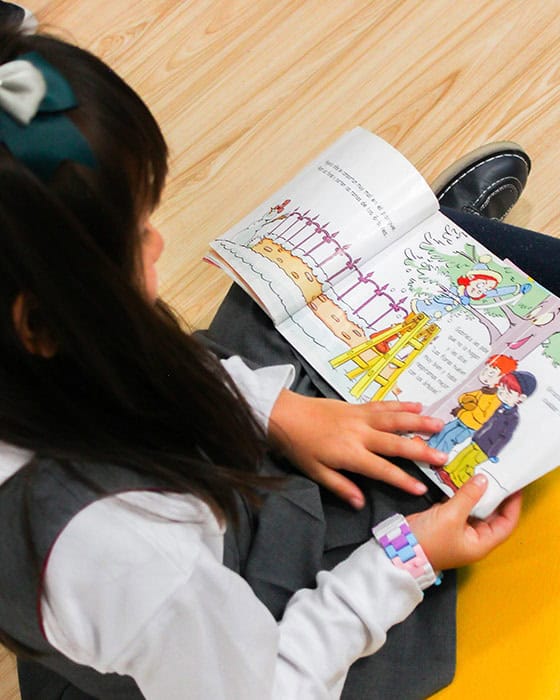 Niña leyendo de forma autónoma en el proyecto educativo de Pequeños Encantos