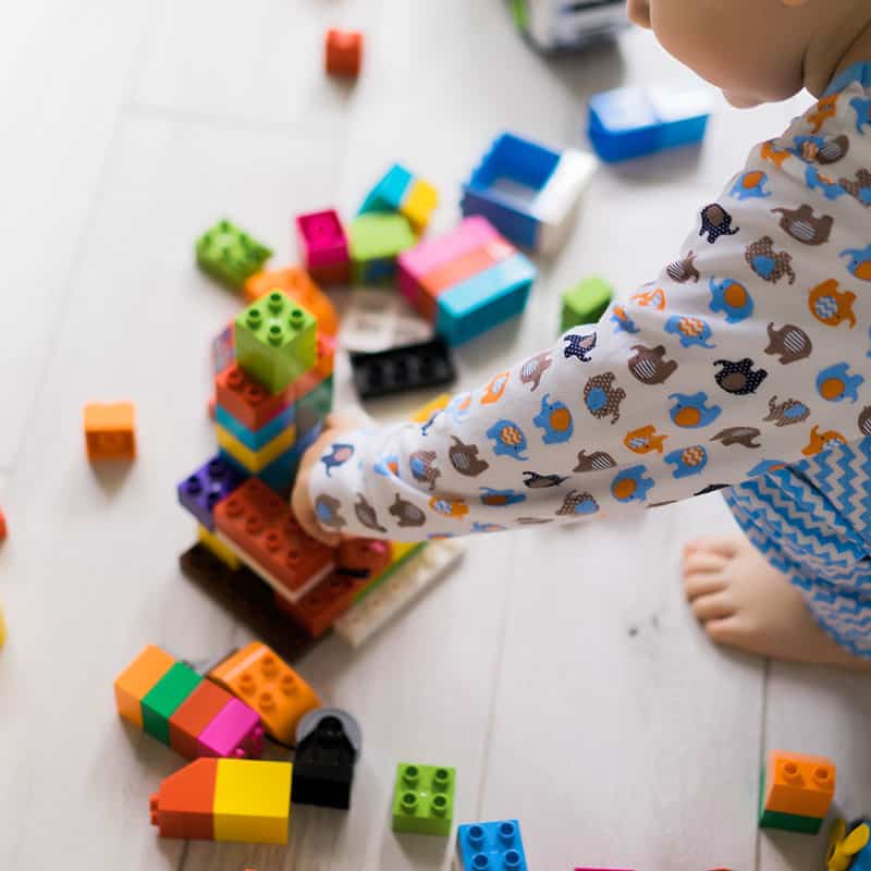 Niño jugando con bloques de colores en el jardín infantil Pequeños Encantos, desarrollo cognitivo y motriz para niños pequeños.