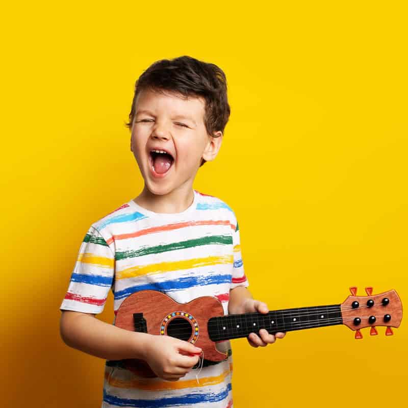 Niño feliz con guitarra en Pequeños Encantos, jardín infantil y educación infantil.